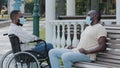 Two African American men in medical masks get together outdoors, greet each other with elbows, abide quarantine rules