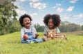 Two African children boy and girl sitting on field grass and eating fruits together in parks and outdoors Royalty Free Stock Photo