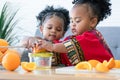Two African cute kid girls squeezing fresh oranges at home. Adorable children siblings help making freshly squeezed orange juice Royalty Free Stock Photo