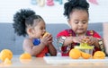 Two African cute kid girls squeezing fresh oranges at home. Adorable children siblings help making freshly squeezed orange juice Royalty Free Stock Photo