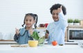 Two African cute sister and brother smiling, thumbs up cheering for eat fresh vegetables at home kitchen. Boy holding green salad Royalty Free Stock Photo