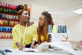 Two african dressmaker woman sews