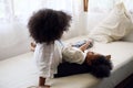Two African girl siblings are having fun and tease each other in the bedroom during the holidays.