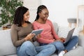 Two african girlfriends spending time at home, using gadgets