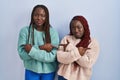 Two african woman standing over blue background pointing to both sides with fingers, different direction disagree Royalty Free Stock Photo