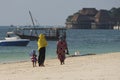 Two African women and a little girl walk along the sandy beach