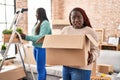 Two african women moving to a new home in shock face, looking skeptical and sarcastic, surprised with open mouth Royalty Free Stock Photo