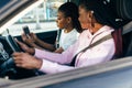 Two african young women driving using navigation on mobile phone on the road trip. Get lost