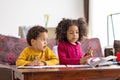 Two afro american kids sititng at home spending qulity time together, drawing writing reading