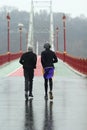 Two afro american men jogging on a rainy foggy day on the downtown Kyiv Pedestrian city bridge