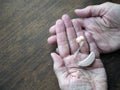 Two aged hands hold a hearing device, copy space. Concept of hearing loss. Assistive technology