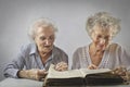 Two aged woomen reading a book Royalty Free Stock Photo