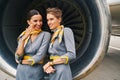 Two air hostesses in uniforms conversing by the aeroengine