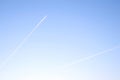 Two airplanes flying on deep blue sky with chemical direction trails.