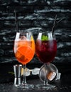 Two alcoholic cocktails. Aperol Sprits, Cocktail with currant. On a wooden background.