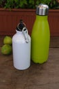 Two aluminium thermal flasks, on a wooden counter, with a vase for flowers and two green figs Royalty Free Stock Photo
