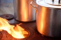 two aluminum pans on wood stove with fire flame beside