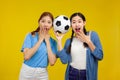 Two Amazed Asian girls football fan over isolated yellow background holding a soccer ball, sport ball concept Royalty Free Stock Photo
