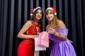 Two amazing women in santa hats and elegant evening dresses holding shopping bags Royalty Free Stock Photo