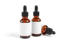 Two amber glass dropper bottles with blank labels and a third bottle lying down Royalty Free Stock Photo