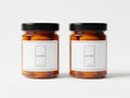 Two amber glass jars with black lids and white labels on a plain white surface Royalty Free Stock Photo