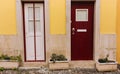 Two ancient wooden doors in Lisbon, Portugal. White and red closed doors with big flower pots. Traditional portuguese exterior.