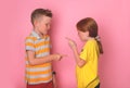 Two angry kids brother and sister standing face to face, pointing fingers to each other, shouting and blame. School
