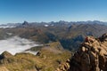 Two anonymous climbers reaching Aspe peak in the Pyrenees with peaks and mountains on the Spanish side and a sea of clouds on the