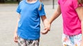 Two anonymous school age children, sisters, siblings together, one girl grabbing, taking other girls hand, kids holding hands