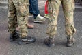 Two anonymous unrecognizable professional soldiers standing on the street, wearing traditional generic camo uniforms, legs closeup