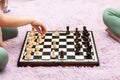 Two anonymous unrecognizable school age children, little girls playing chess in their room at home, chess board on the ground Royalty Free Stock Photo