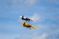 Two Antonov AN-2 biplane fly on cloudy sky. Old yellow and blue historic plane from back