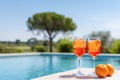 Two Aperol Spritz cocktails with ice and orange slices by a sunny poolside. Royalty Free Stock Photo