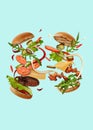 Two appetizing burgers with flying ingredients against turquoise background. Ham, beef cutlet, cheese, ketchup Royalty Free Stock Photo