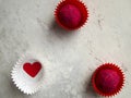 Two appetizing pink candies in red candy wrappers and a red heart in a white wrapper on a gray background.