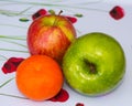 Two apples and a small mandarin orange that are part of a weekly grocery shop provide an essential element of the 5 a day eating m