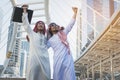 Two Arab businessmen standing by raising both hands