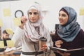 Two arab women working in office. Coworkers are taking notes on glass board. Royalty Free Stock Photo