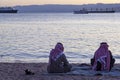 Two Arabic men wearing keffiyeh, agal and thobe are seen on the beach by the Gulf of Aqaba,