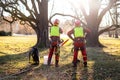 Two arborist men standing against two big trees. The worker with helmet working at height on the trees. Lumberjack working with ch Royalty Free Stock Photo