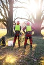 Two arborist men standing against two big trees. The worker with helmet working at height on the trees. Lumberjack working with ch Royalty Free Stock Photo