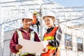 Two architect and client discussing help create plan with blueprint home building at construction site Royalty Free Stock Photo