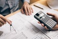 Two architect working at construction site and compass drawing pointing on blueprint with calculator calculate Royalty Free Stock Photo