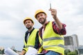 two architects in safety vests and hardhats working with blueprints and pointing Royalty Free Stock Photo