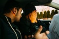 Two armed bandits sitting in a car planning their next robbery, while counting on a stopwatch the time they have for the robbery, Royalty Free Stock Photo