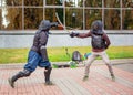 Two armed men lead a sword fight, a medieval fight, at a fun medieval tournament. Sports competitions