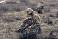 Two armed Ukrainian soldiers sit and rest in steppe against background of dry grass