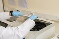 Two arms of a lab technician and both hands with blue nitril gloves closing a centrifuge. Royalty Free Stock Photo