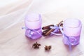 Two aromatic candles in glass candlesticks with lavender paper, cinnamon and anise on table close up