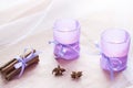 Two aromatic candles in glass candlesticks with lavender paper, cinnamon and anise on table close up